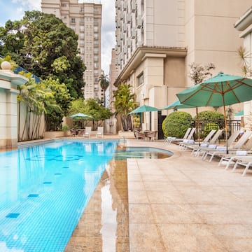 a pool with umbrellas and chairs in front of a building