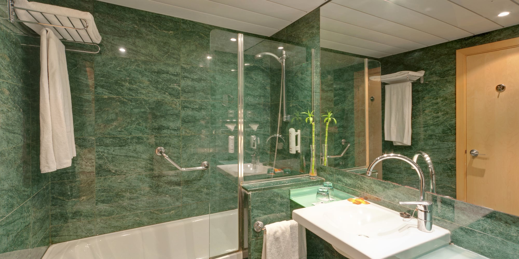 a bathroom with green marble walls and a sink and shower