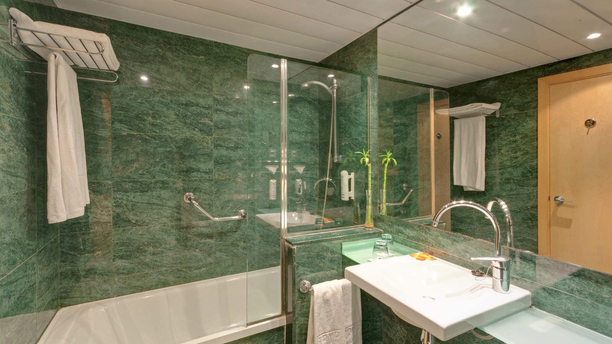 a bathroom with green marble walls and a sink and shower
