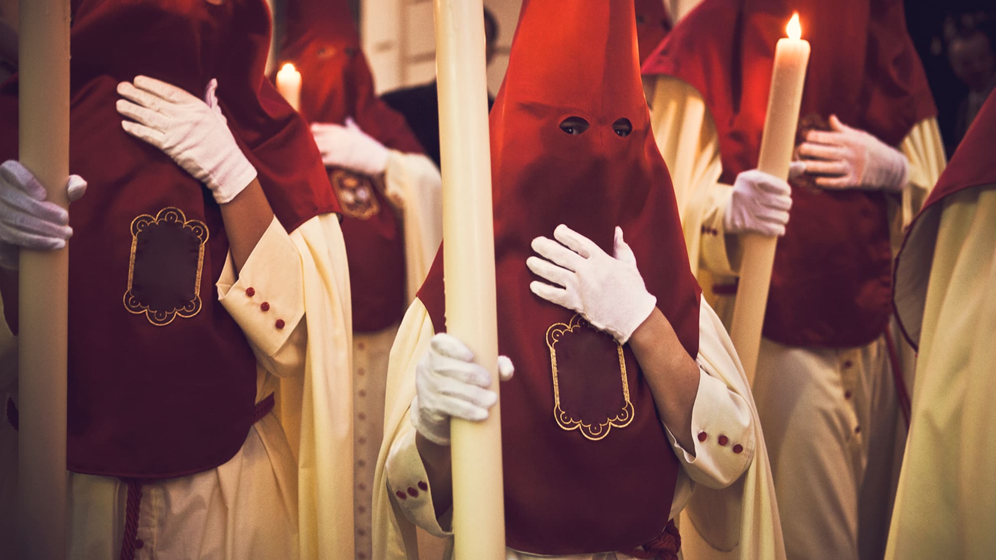 a group of people wearing white gloves holding a candle