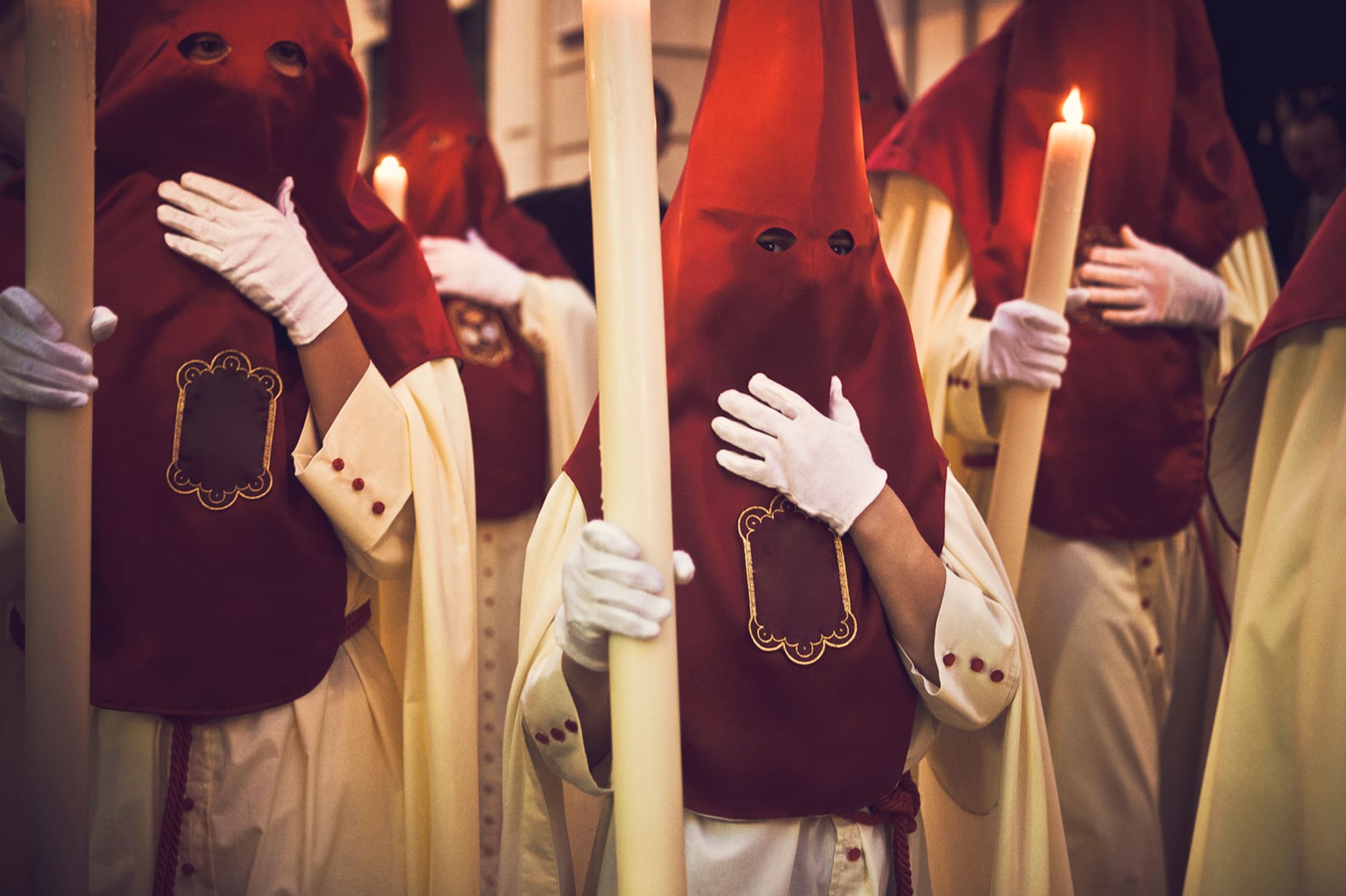 a group of people wearing white gloves holding a candle
