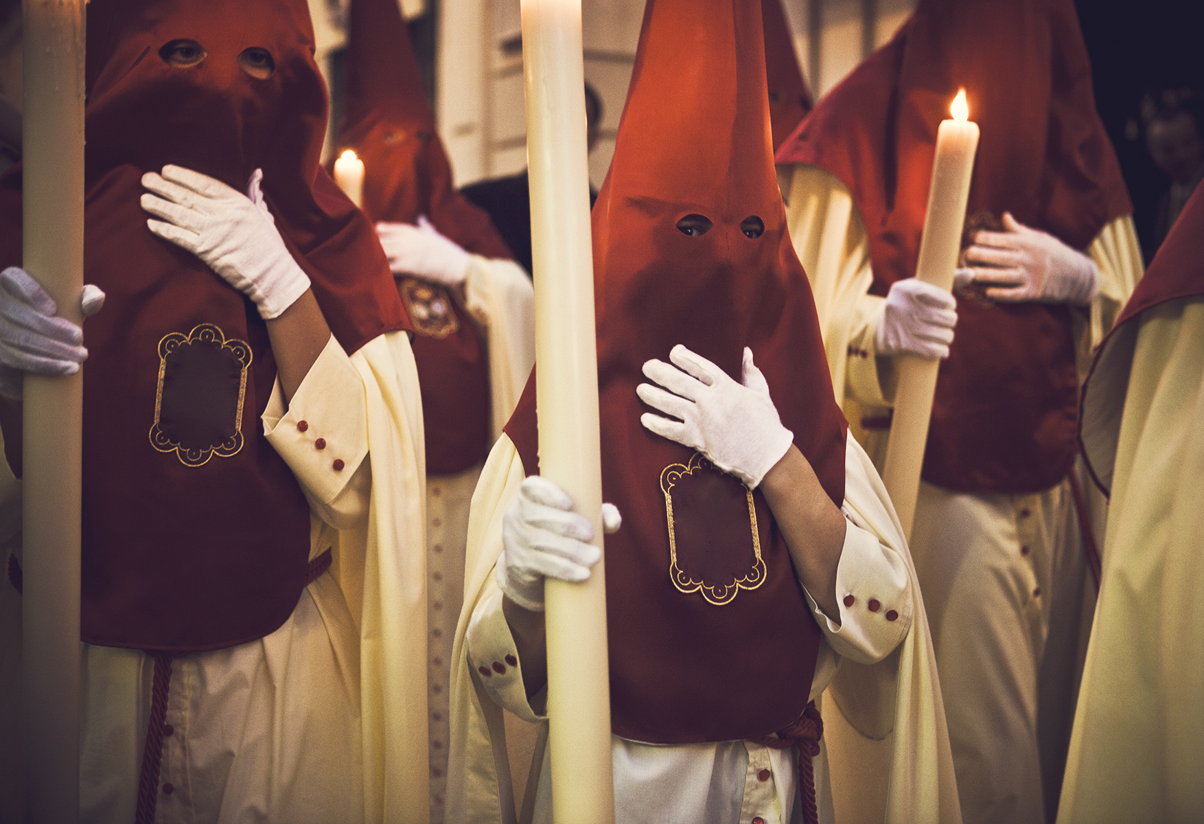 a group of people wearing white gloves holding a candle