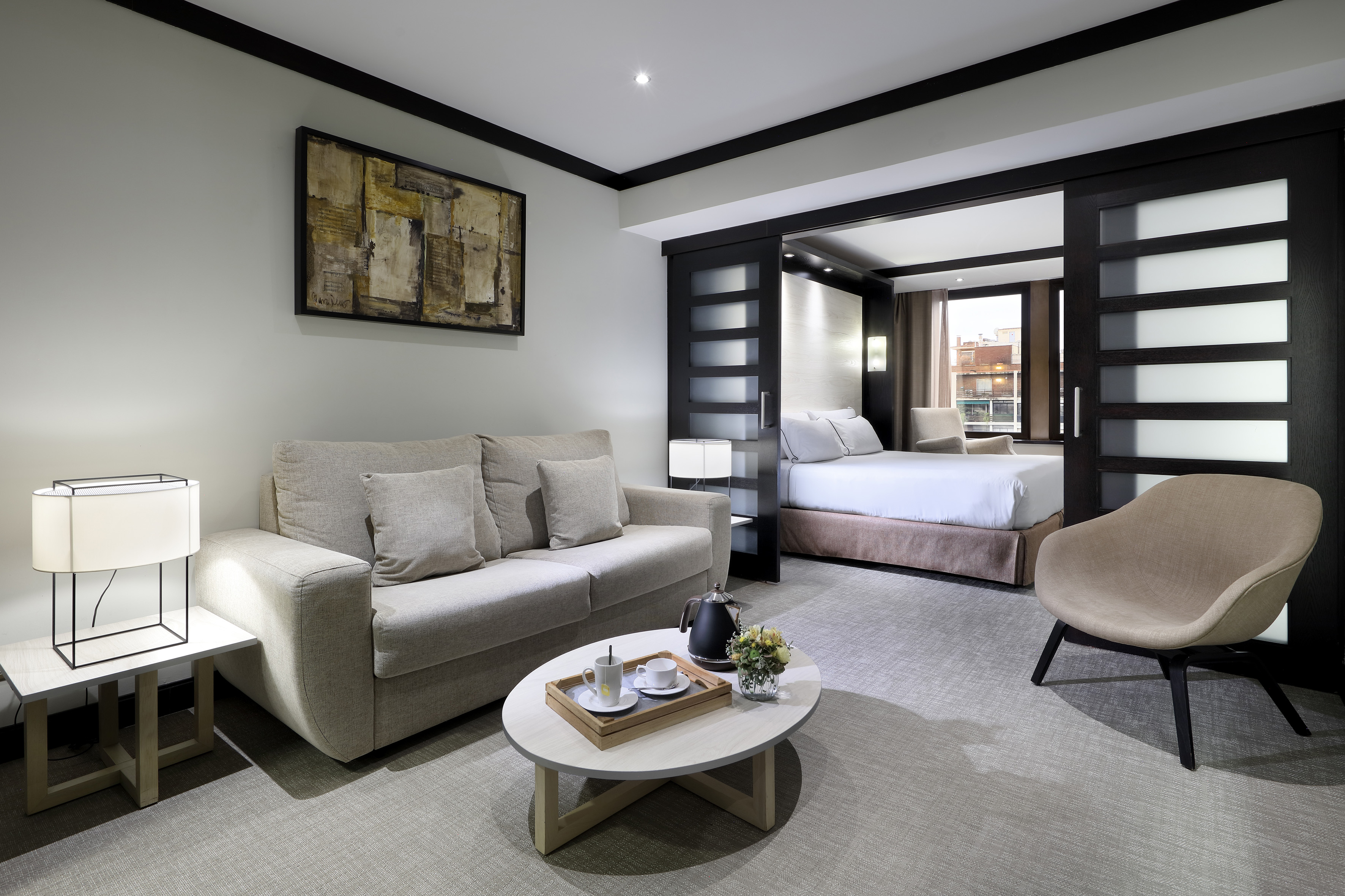 Modern hotel suite with living area, sofa, and cozy separate bedroom.