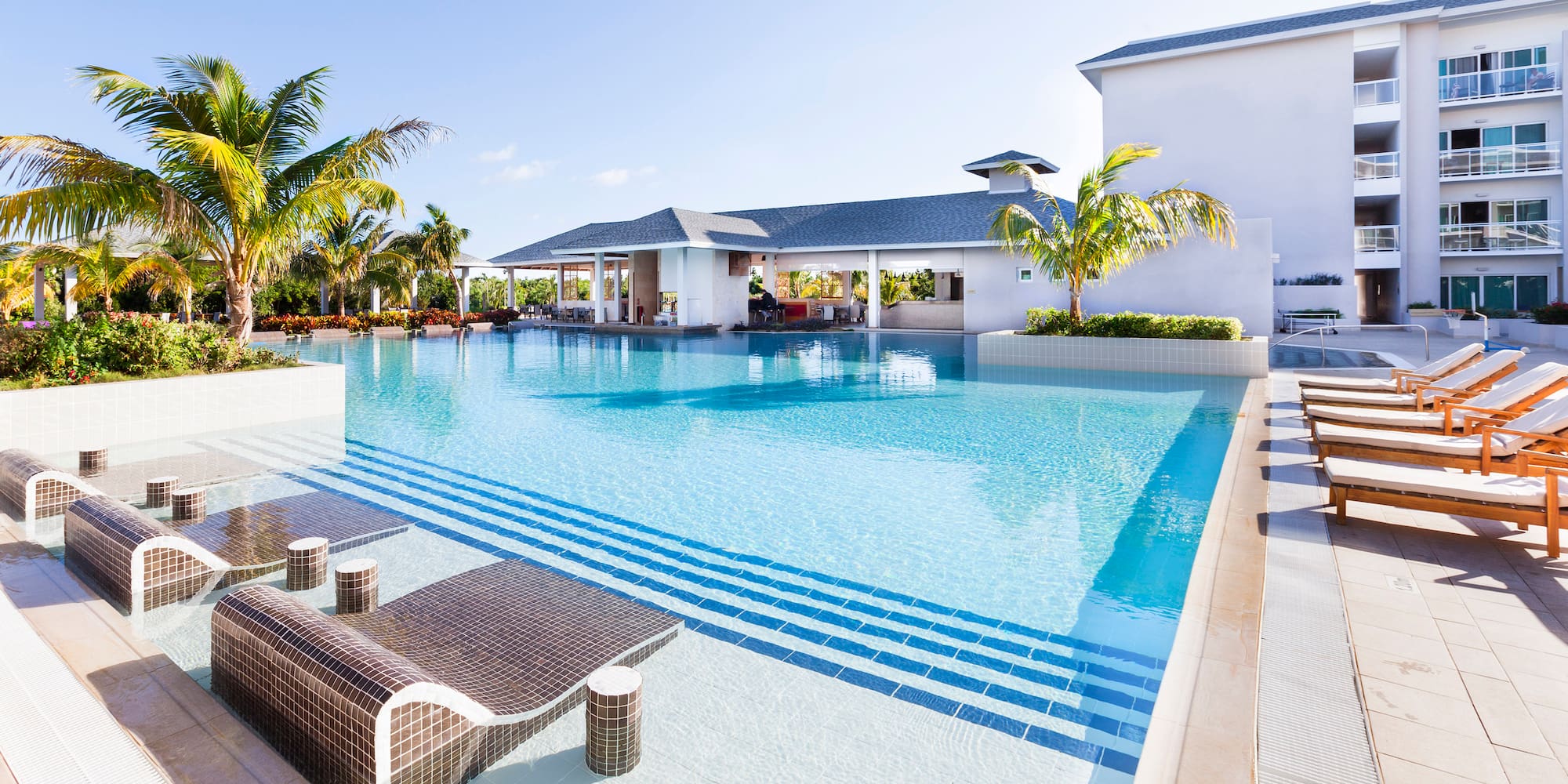 a swimming pool with lounge chairs and palm trees