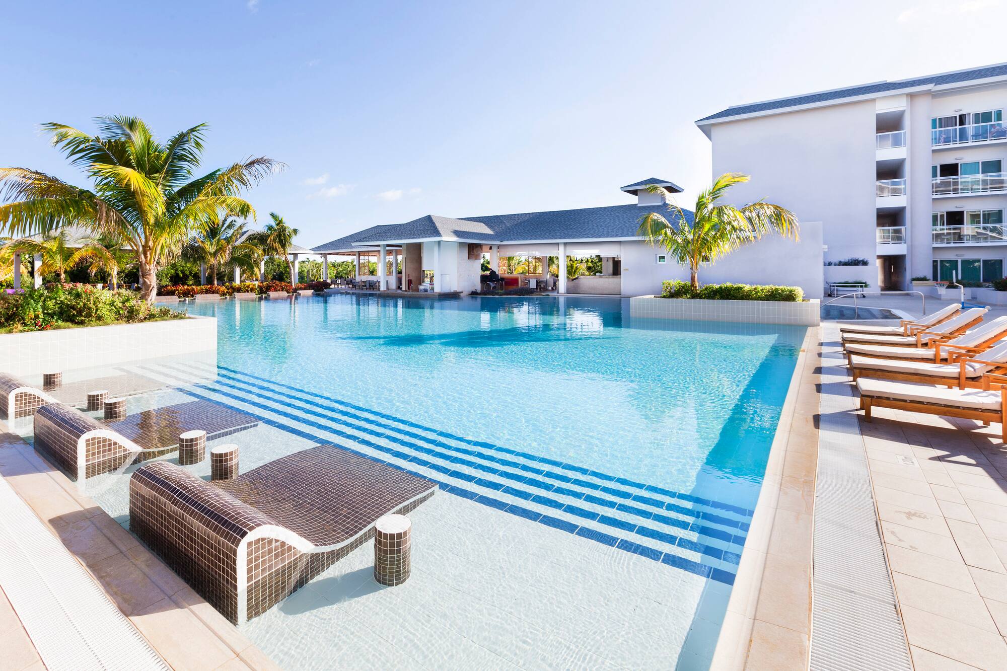 a swimming pool with lounge chairs and palm trees
