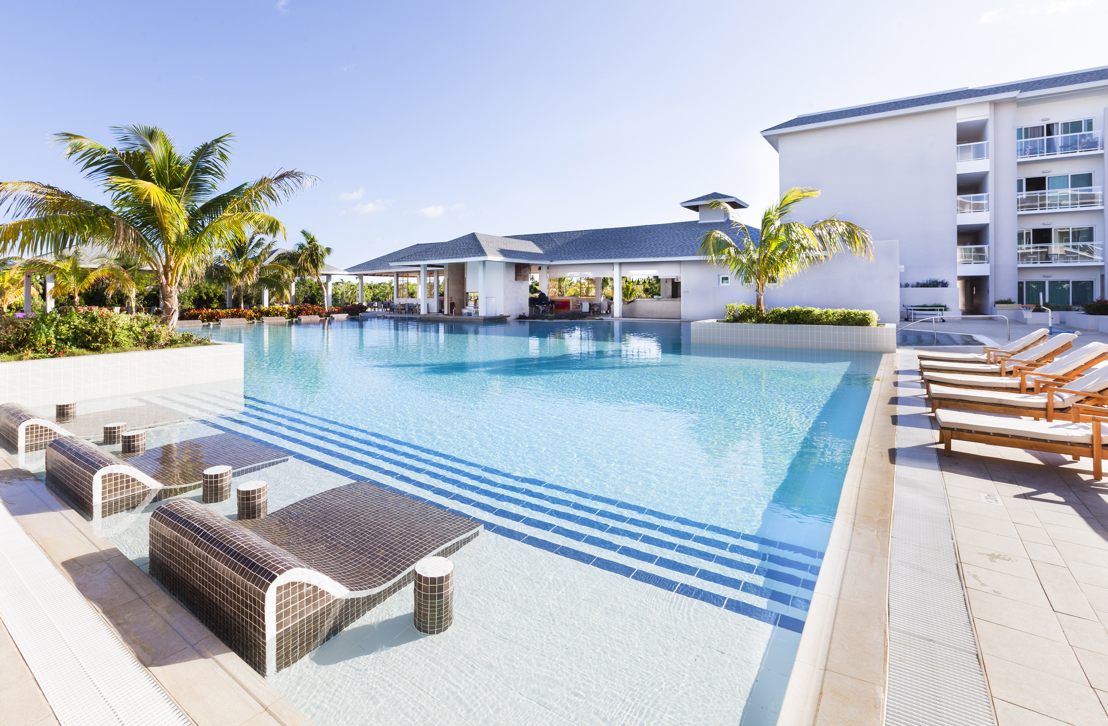 a swimming pool with lounge chairs and palm trees