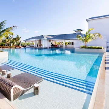 a swimming pool with lounge chairs and palm trees