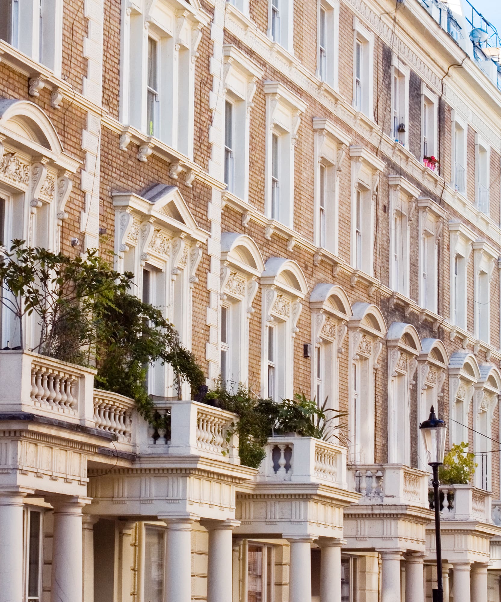 Fachadas victorianas de ladrillo con balcones ornamentados en Londres.