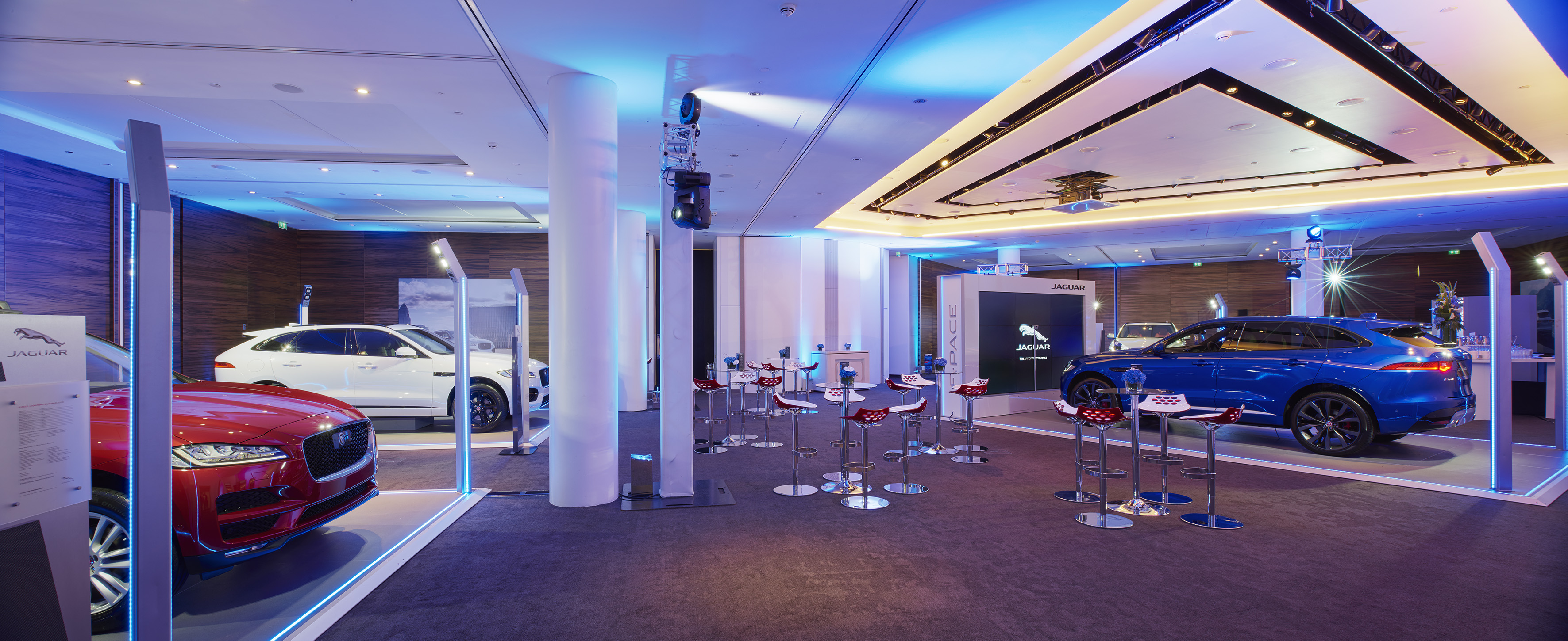 Jaguar F-Pace SUV models showcased in a modern, blue-lit automotive event.