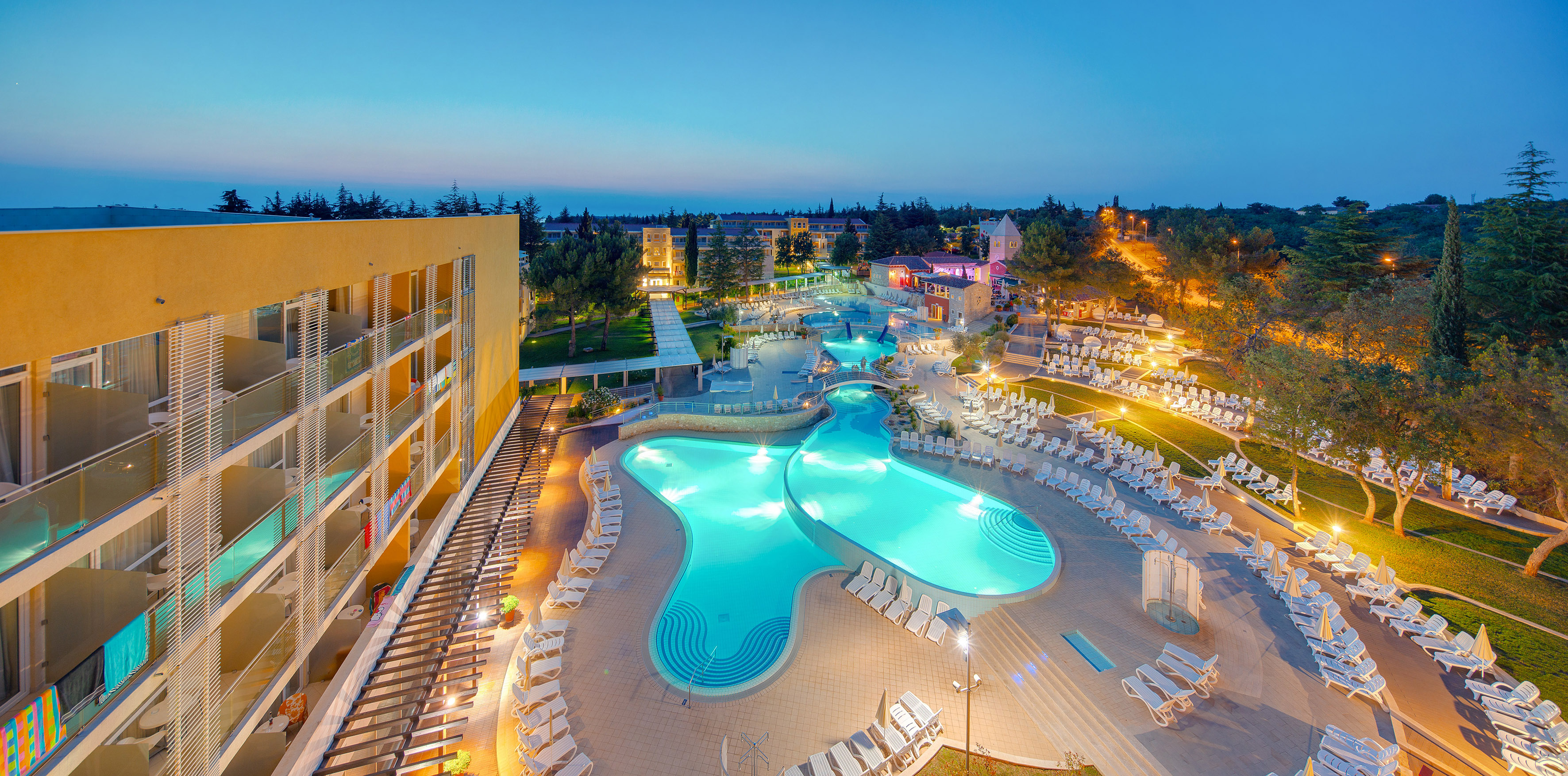 a pool with chairs and a building in the background