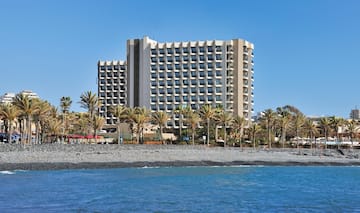 a building with many windows and palm trees by the water