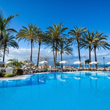 a pool with palm trees and umbrellas