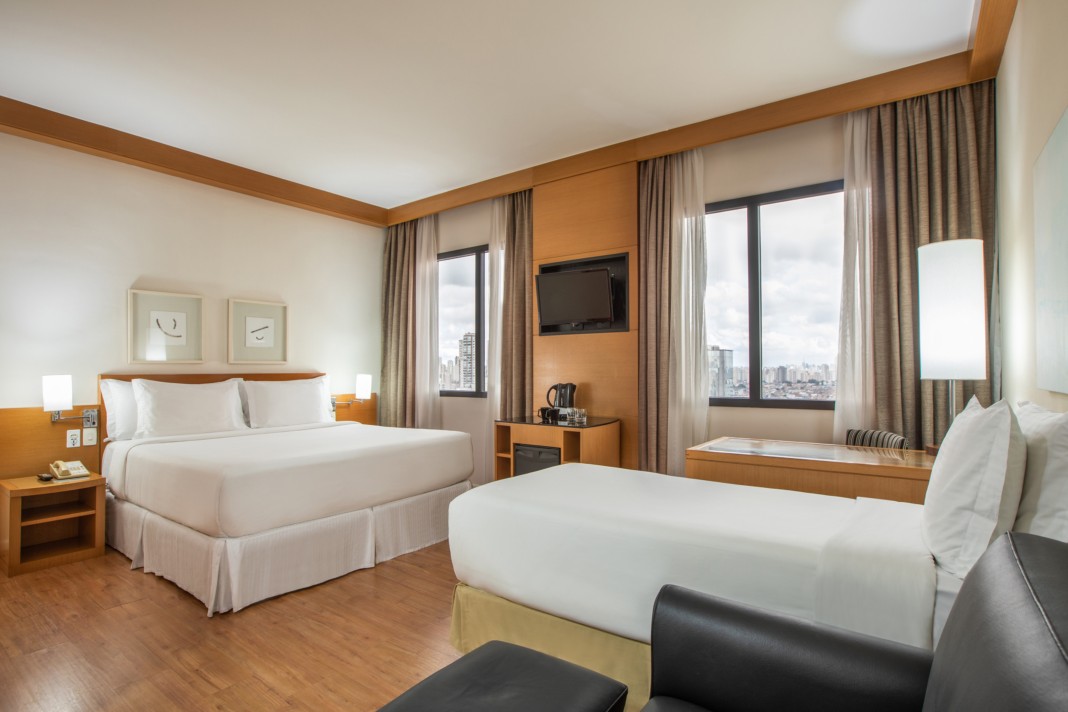 Modern hotel guest room with two beds, city view, and wood accents.