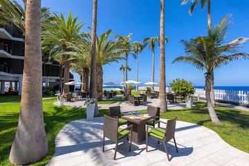 a patio area with chairs and tables and palm trees