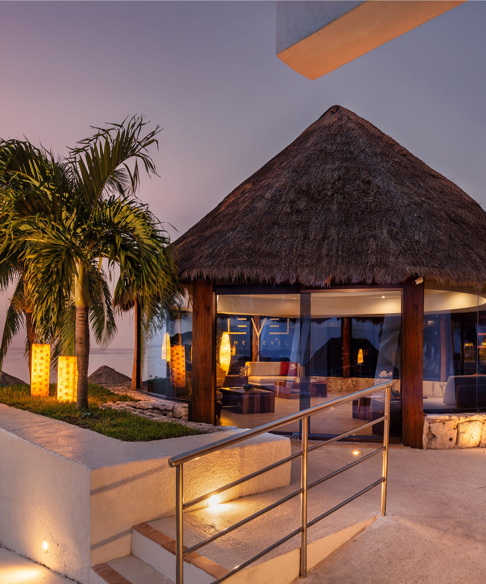 a building with a thatched roof and palm trees