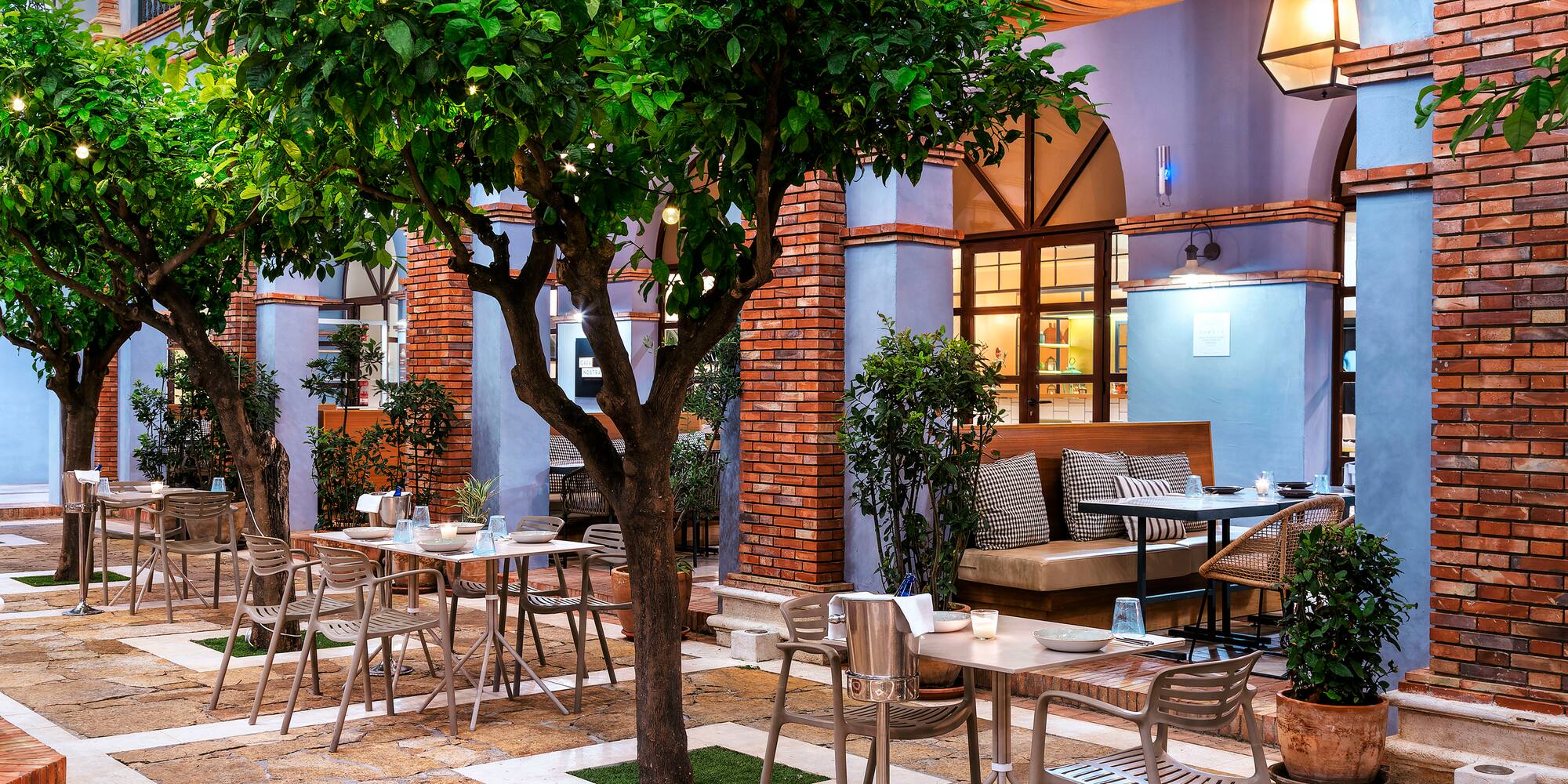 a patio with tables and chairs and a tree