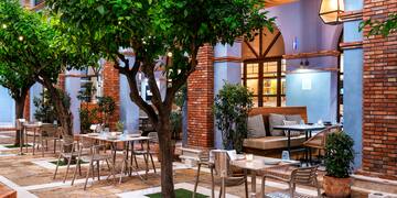 a patio with tables and chairs and a tree