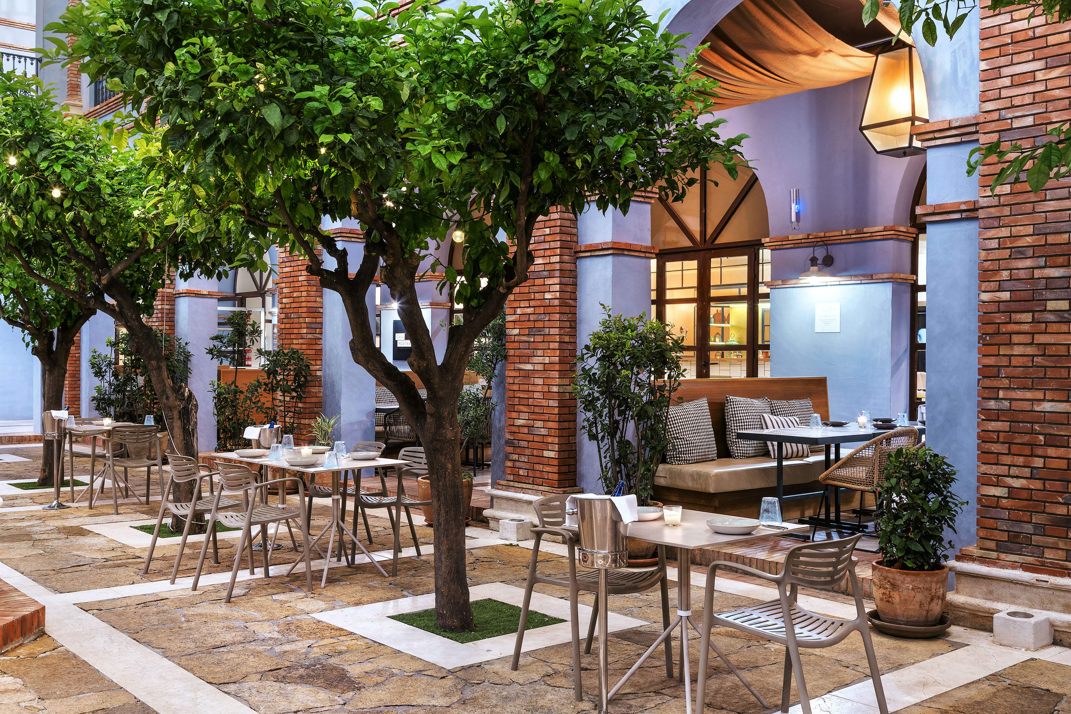 Mediterranean style outdoor dining patio with illuminated trees and seating.