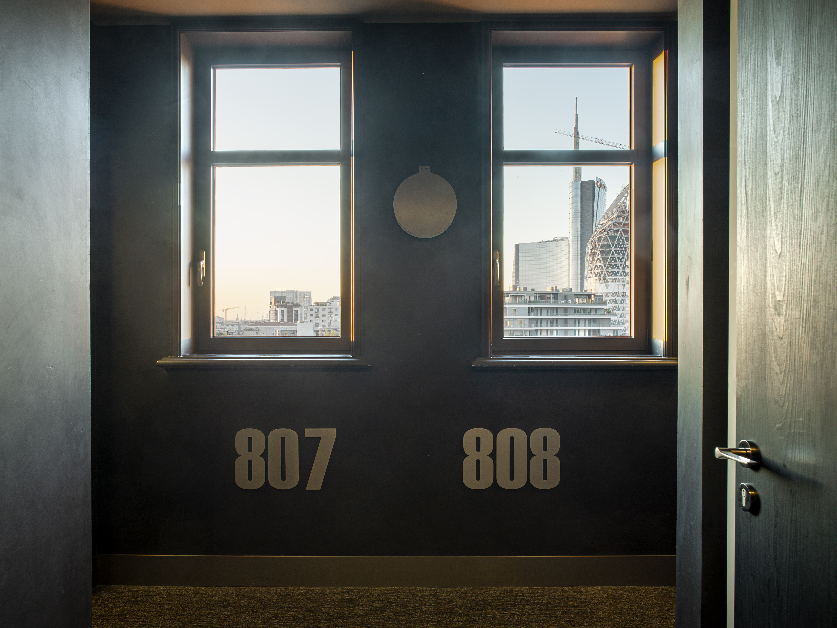 Modern hotel hallway 807, 808, with Milan skyline view from windows.