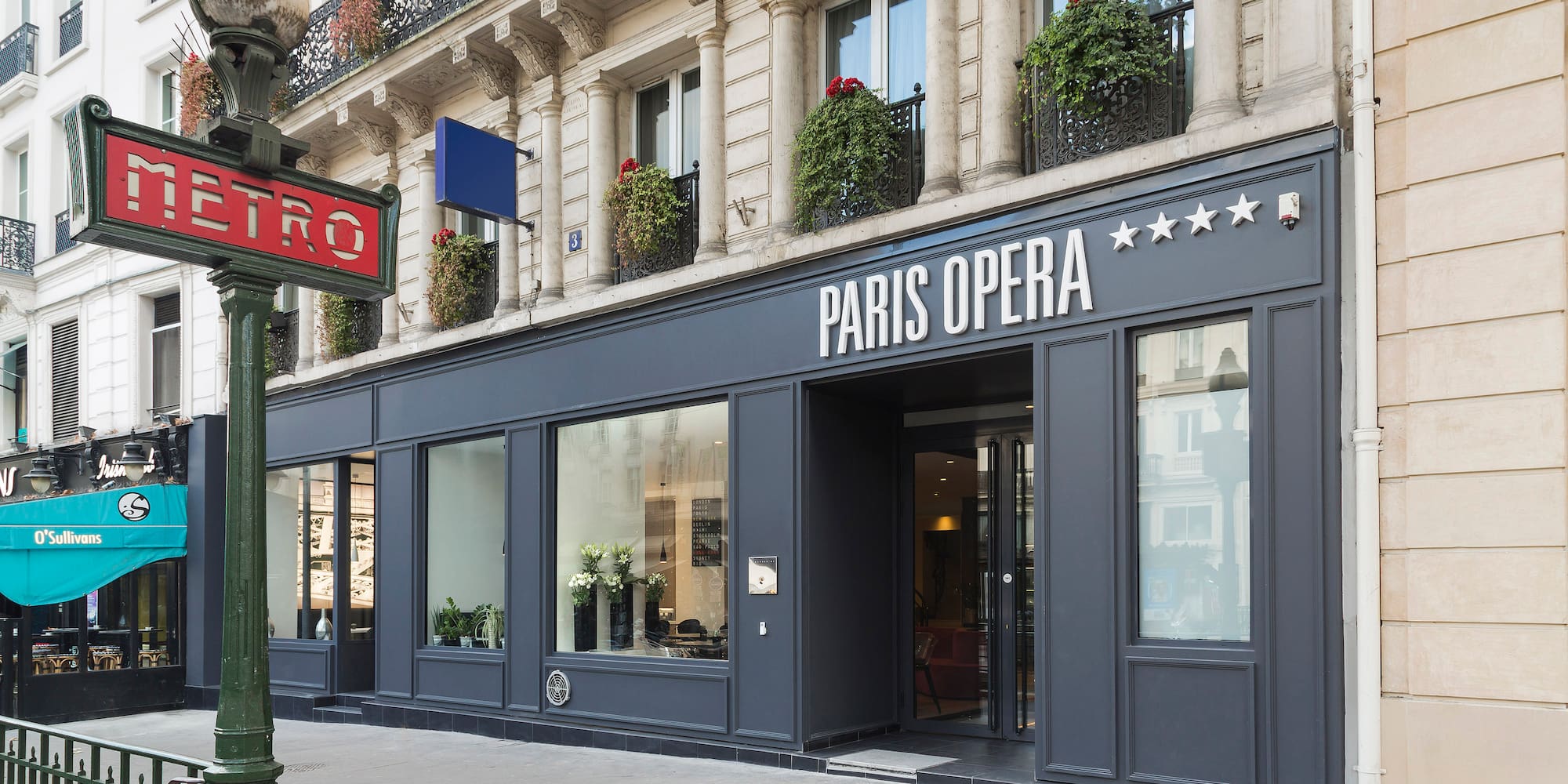 Classic Paris street with Metro sign and Paris Opera 5-star hotel facade.
