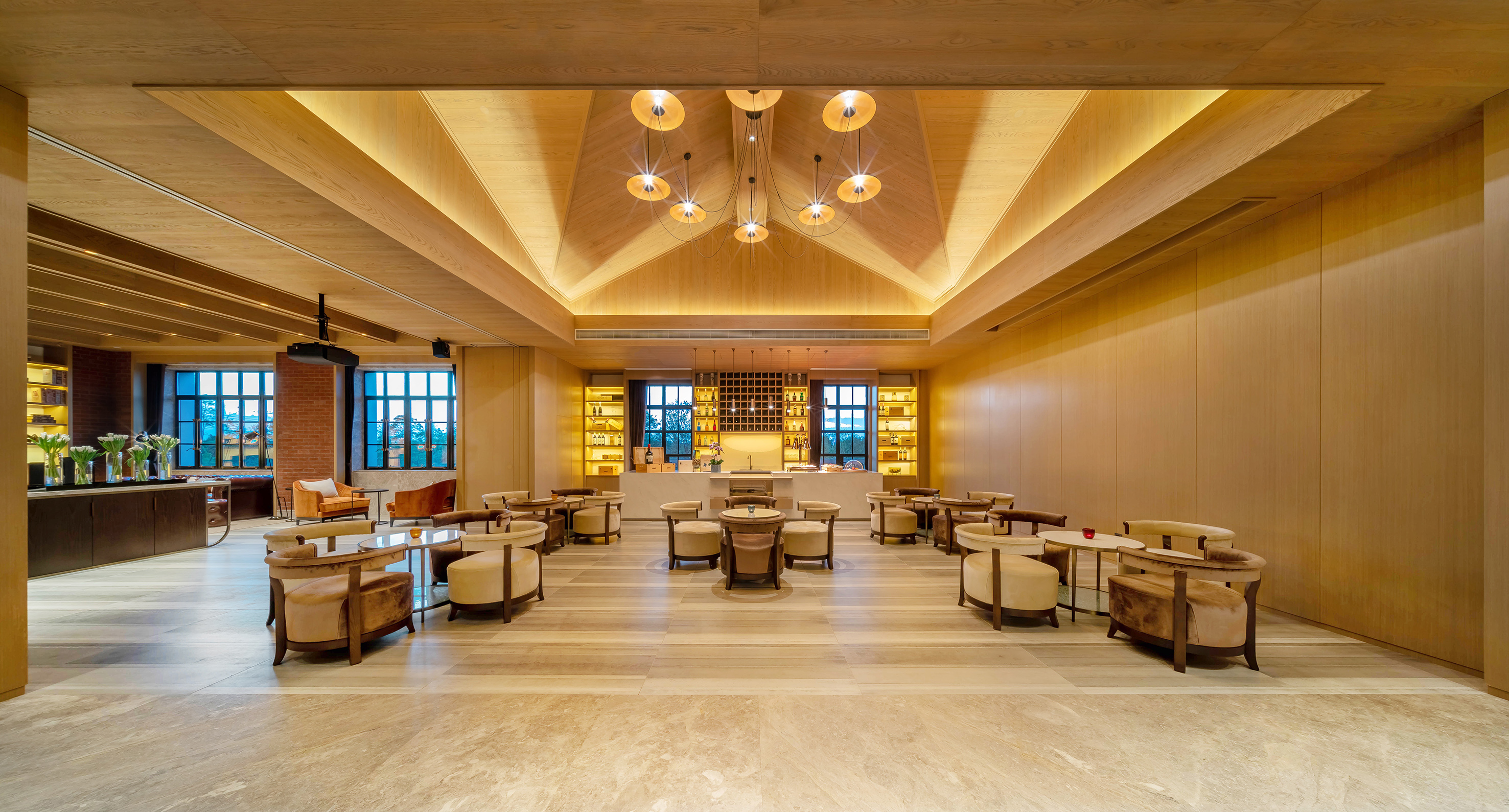 Modern hotel lounge: wood vaulted ceiling, chandelier, bar, and seating.