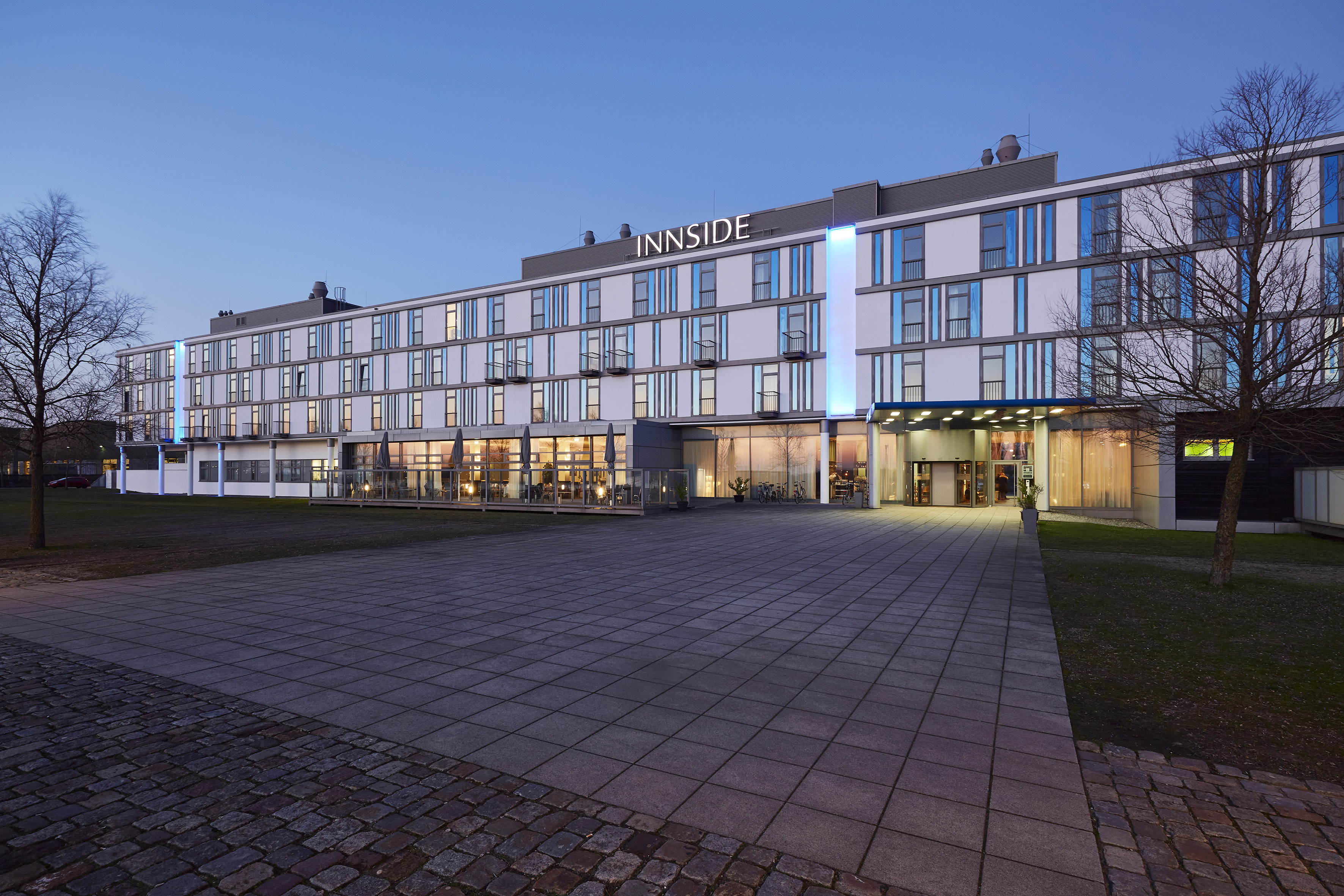 Modern INNSIDE hotel exterior at dusk, illuminated facade and entrance.