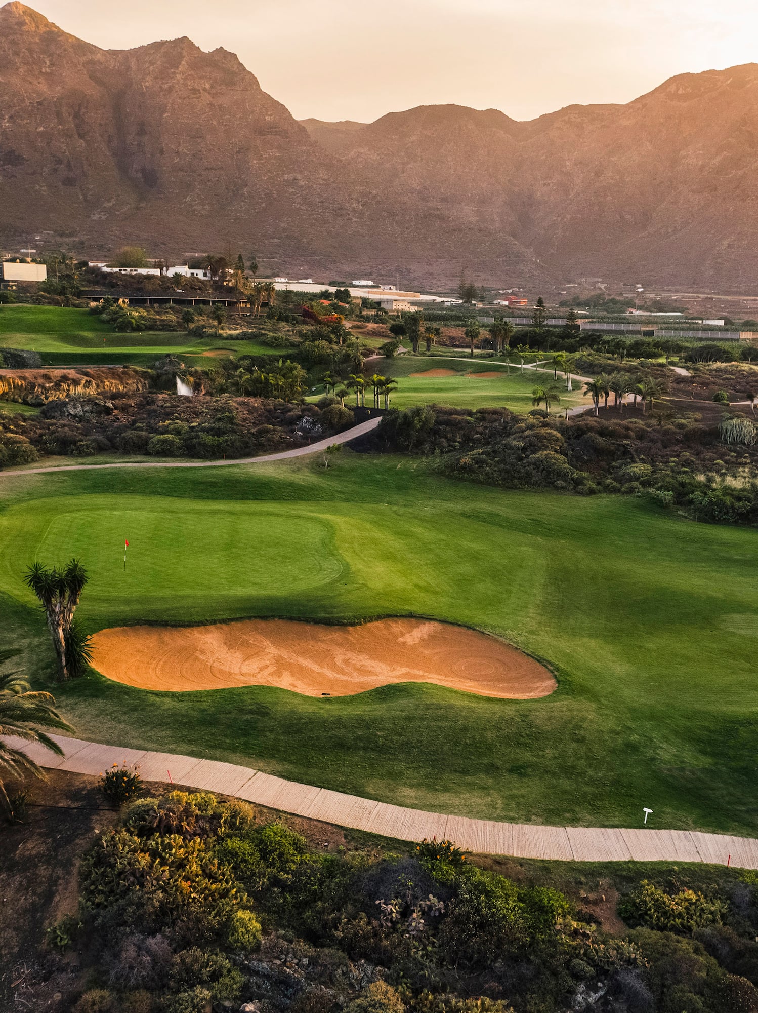 a golf course with a path and a hill in the background
