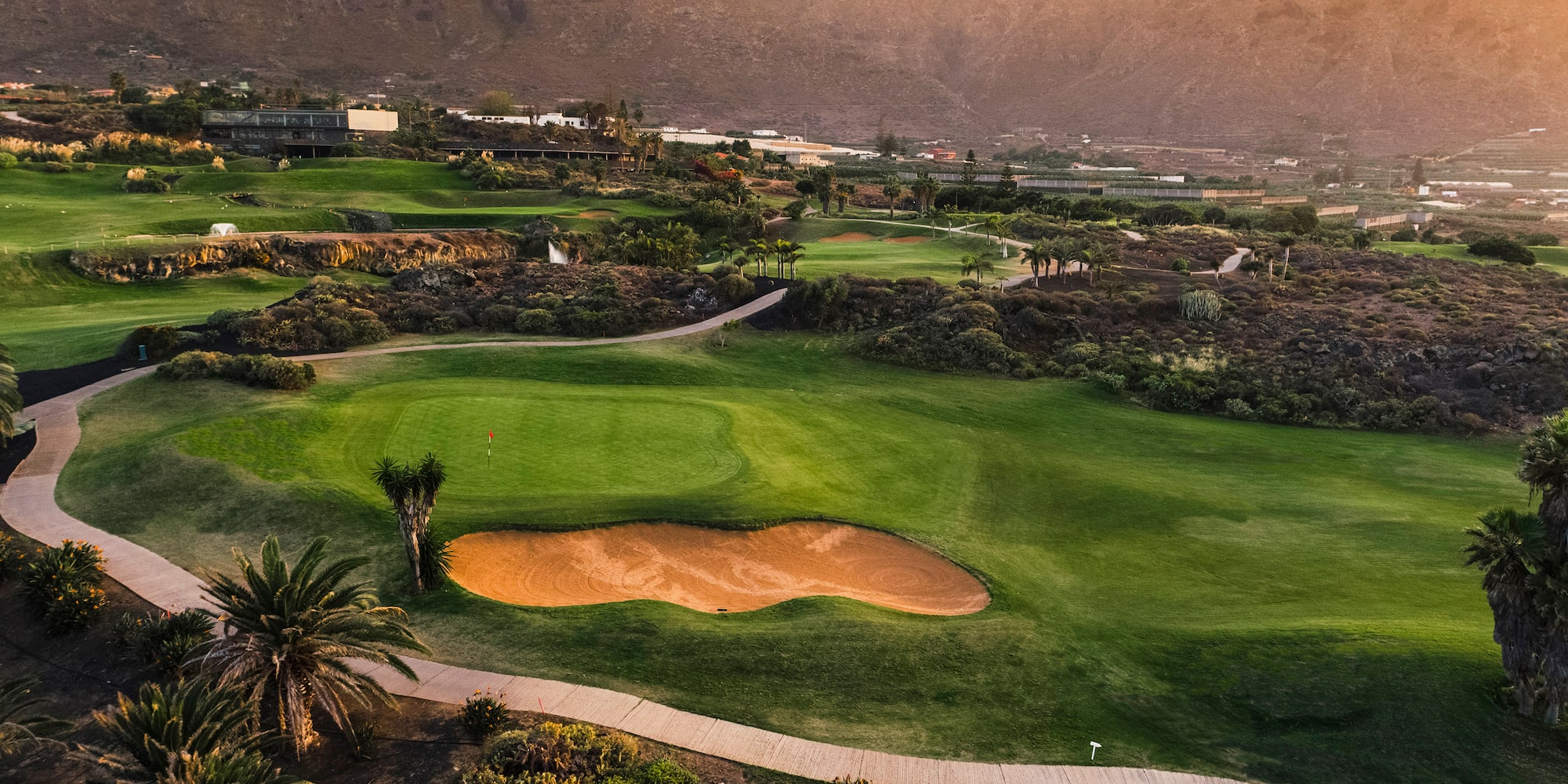a golf course with a path and a hill in the background