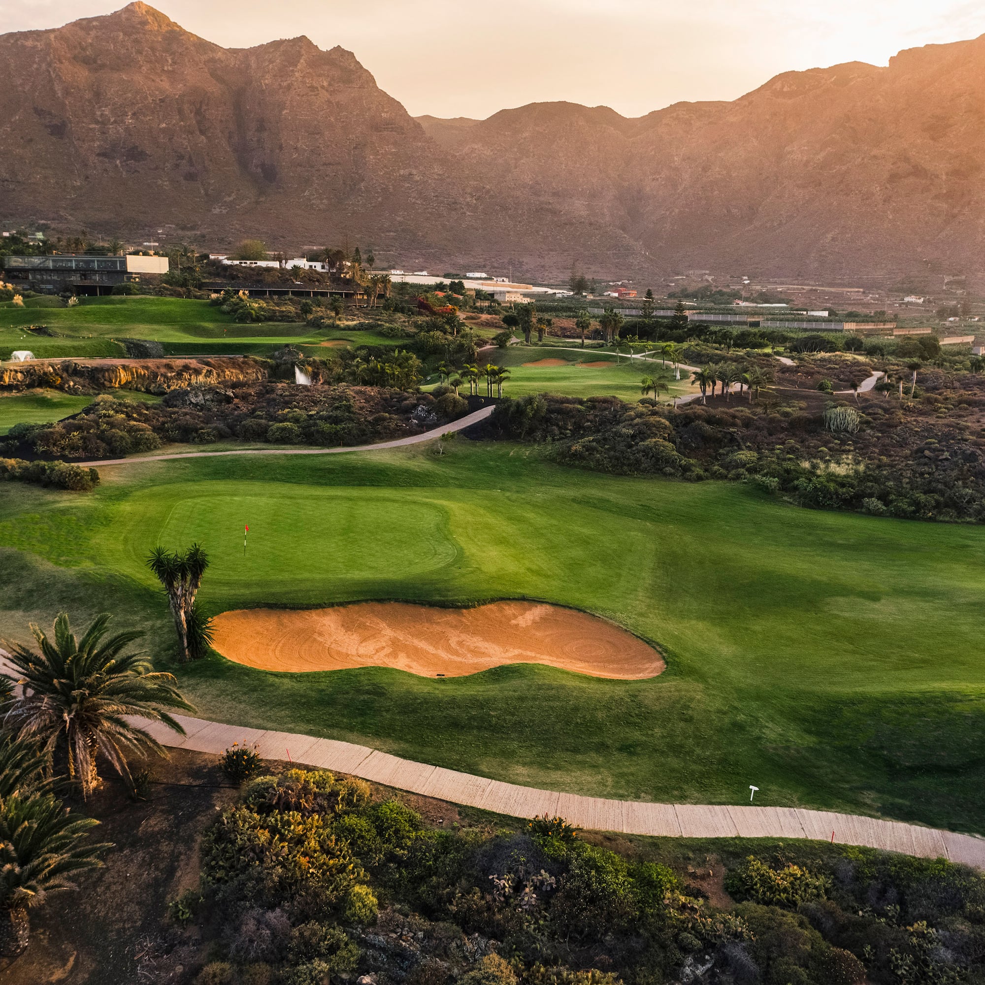 a golf course with a path and a hill in the background