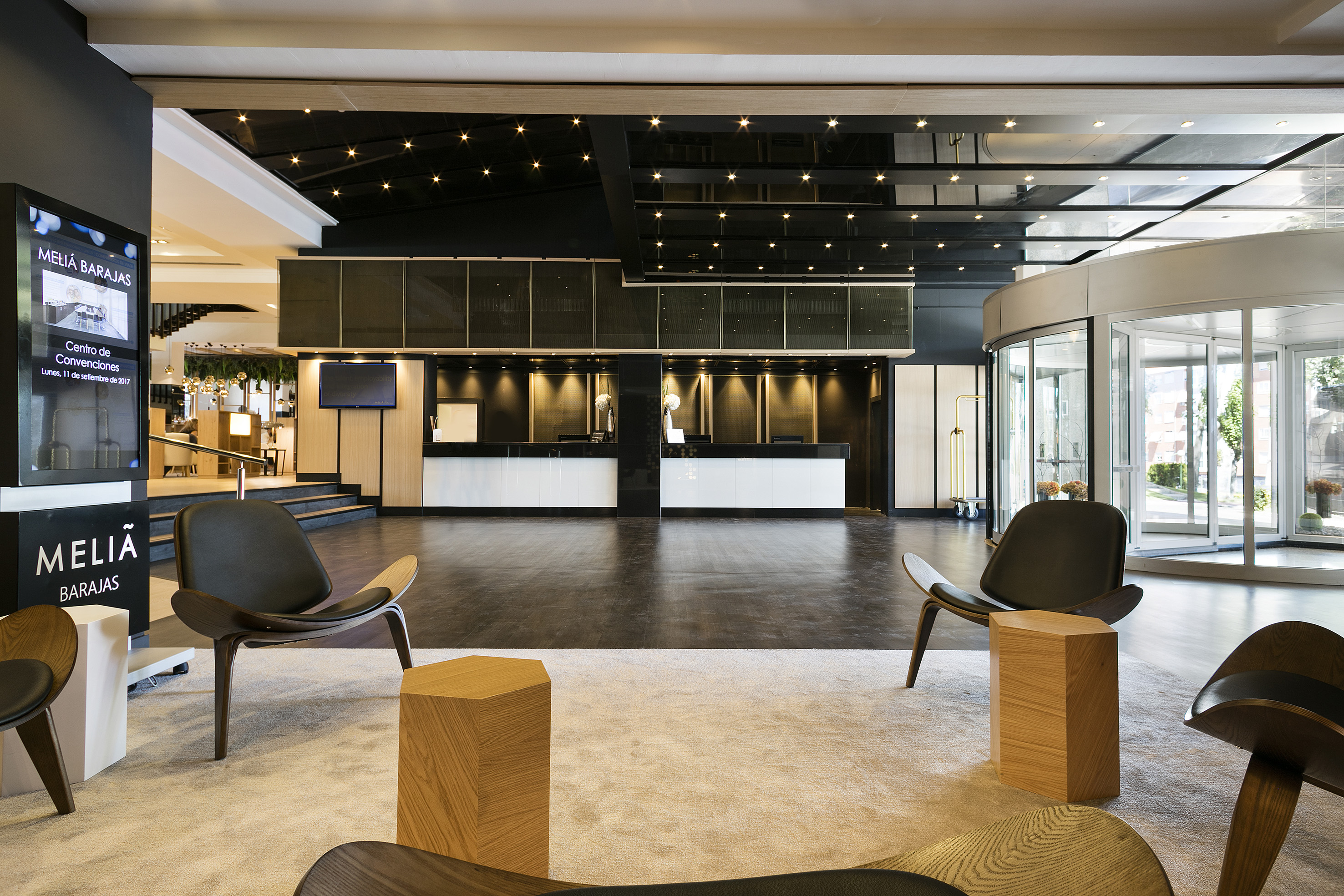 Modern Melia Barajas hotel lobby with reception, lounge seating, and entrance.