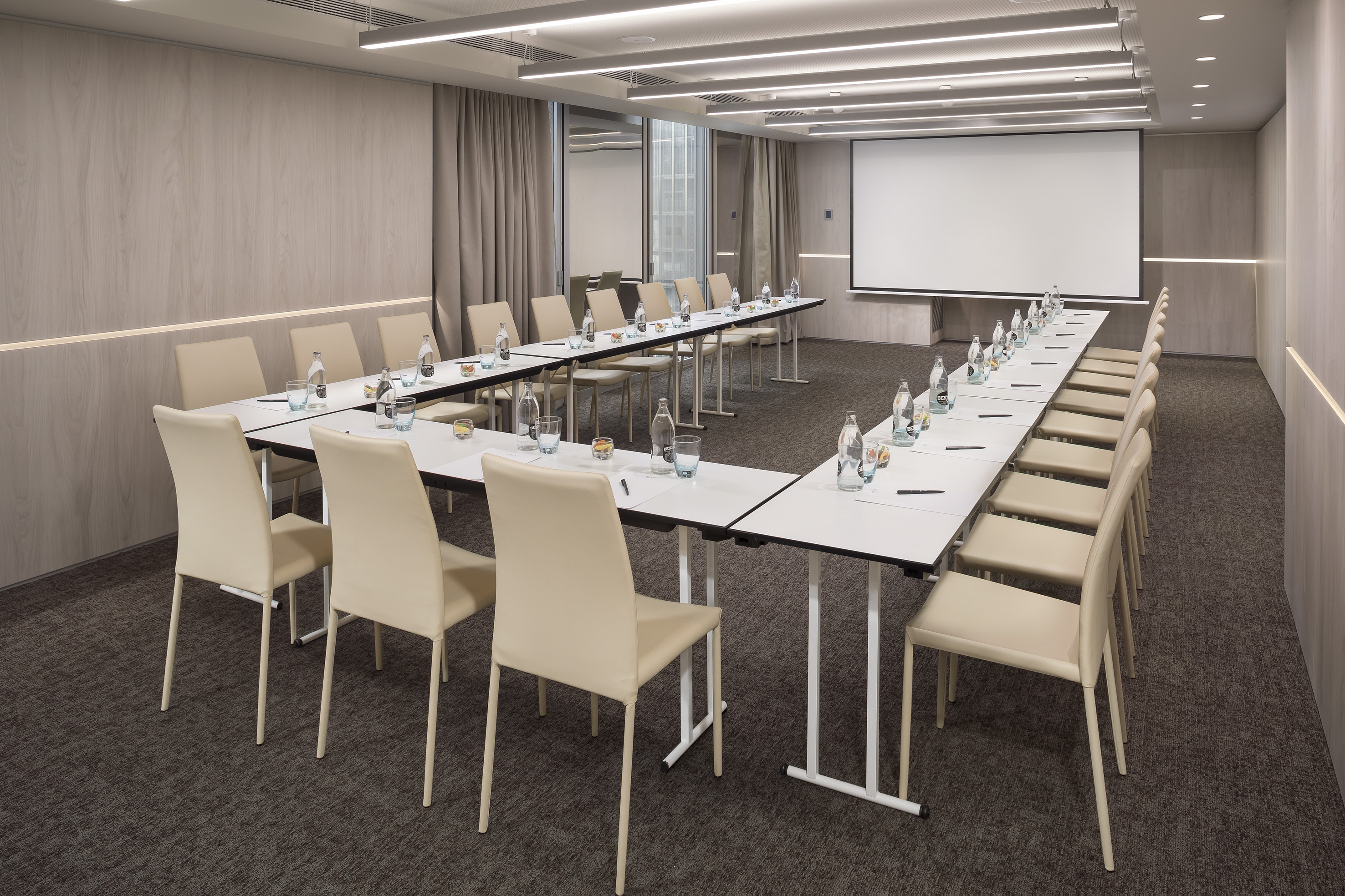 U-shaped conference room for meetings with presentation screen and chairs.