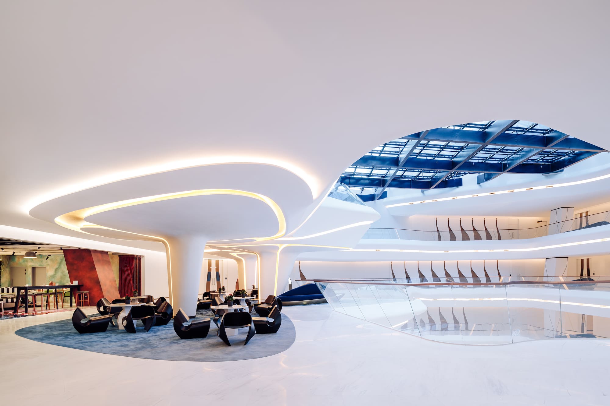 Sleek white multi-level interior with curved architecture, lounge seating, and skylight.