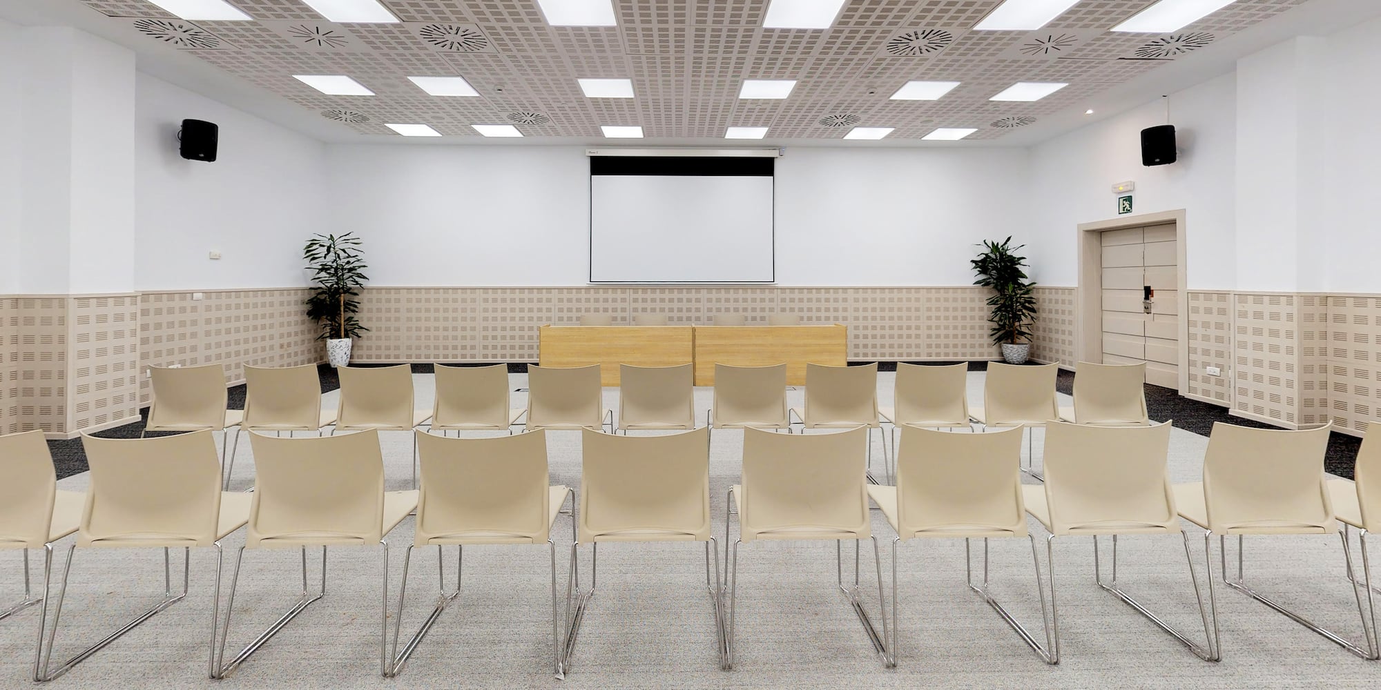 a room with white chairs and a screen