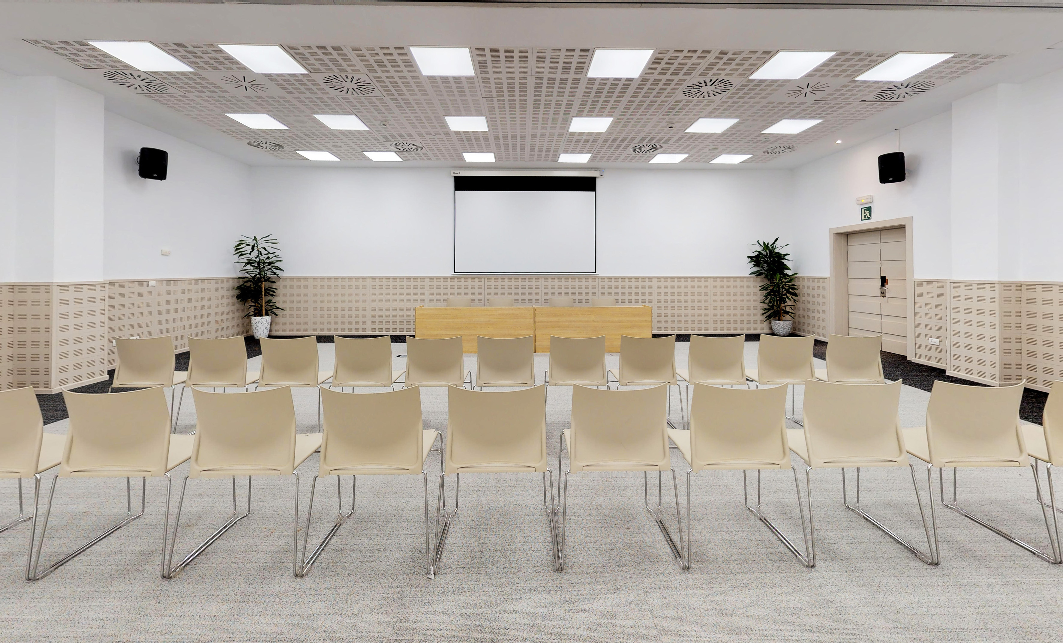 a room with white chairs and a screen