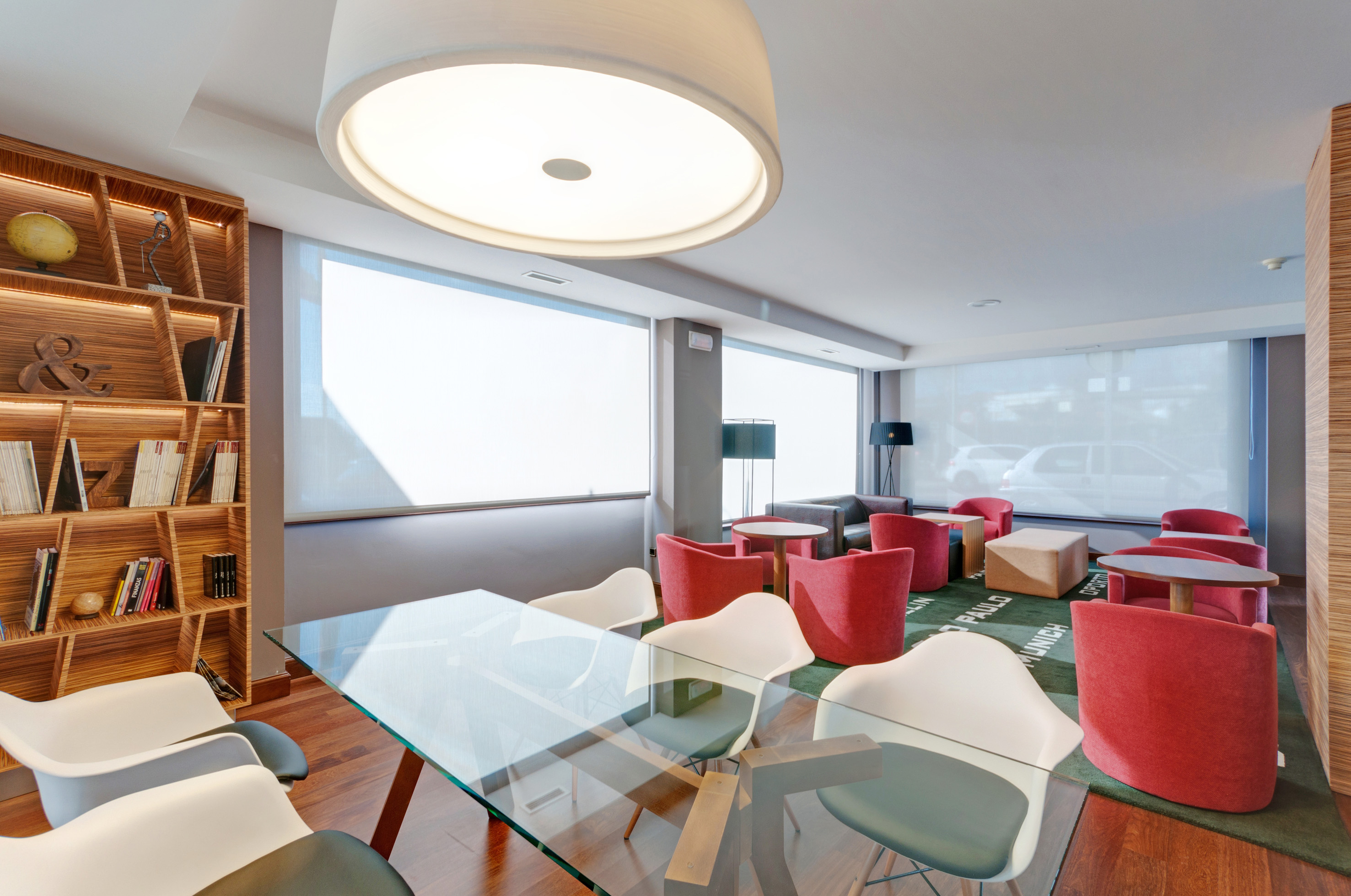 Contemporary lobby with diverse seating, glass table, and illuminated bookcase.