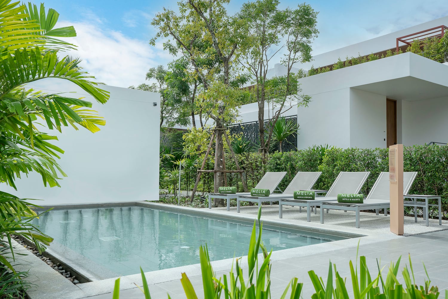 a pool with lounge chairs and trees in the background