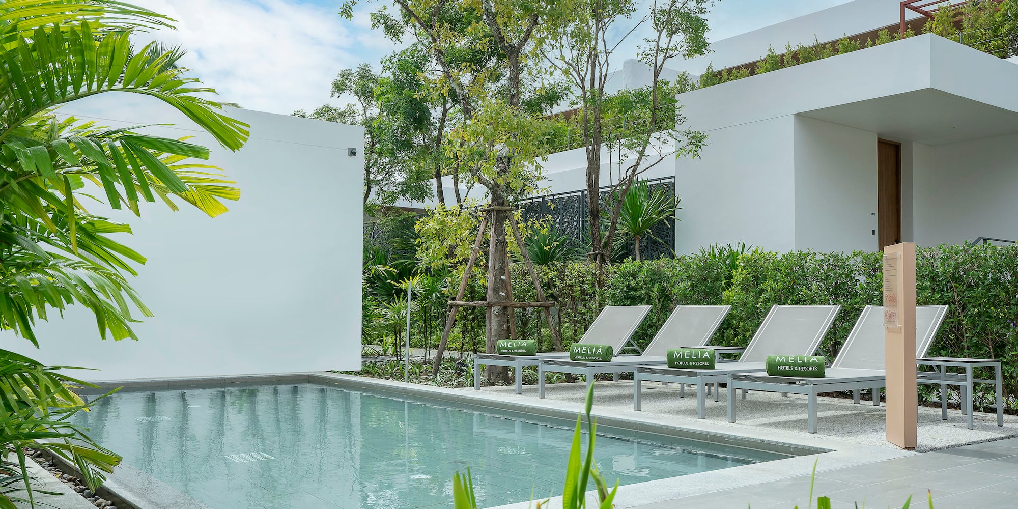 a pool with lounge chairs and trees in the background