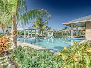 a pool with palm trees and a pool with a deck and chairs
