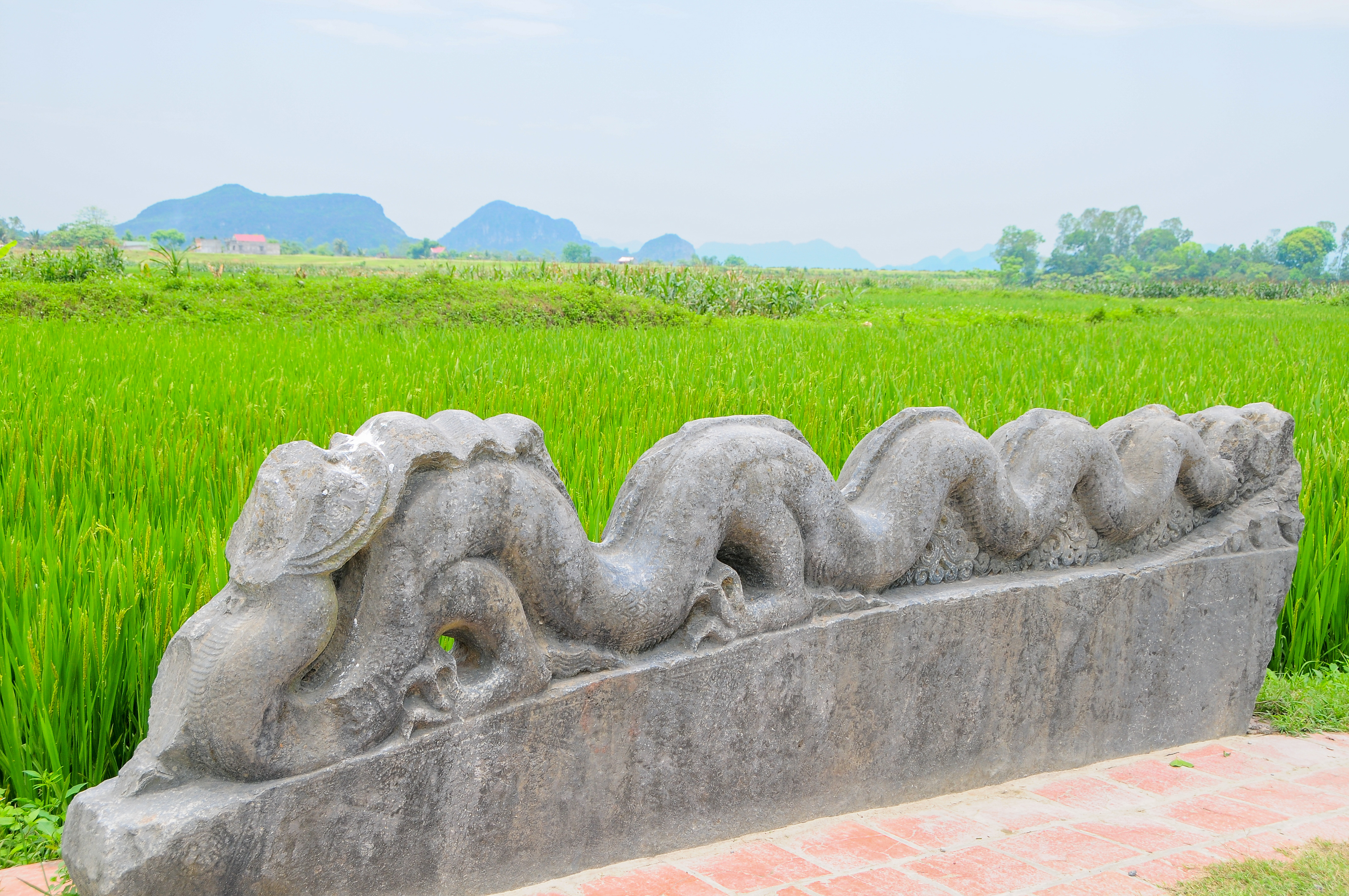 a stone dragon sculpture in front of a green field