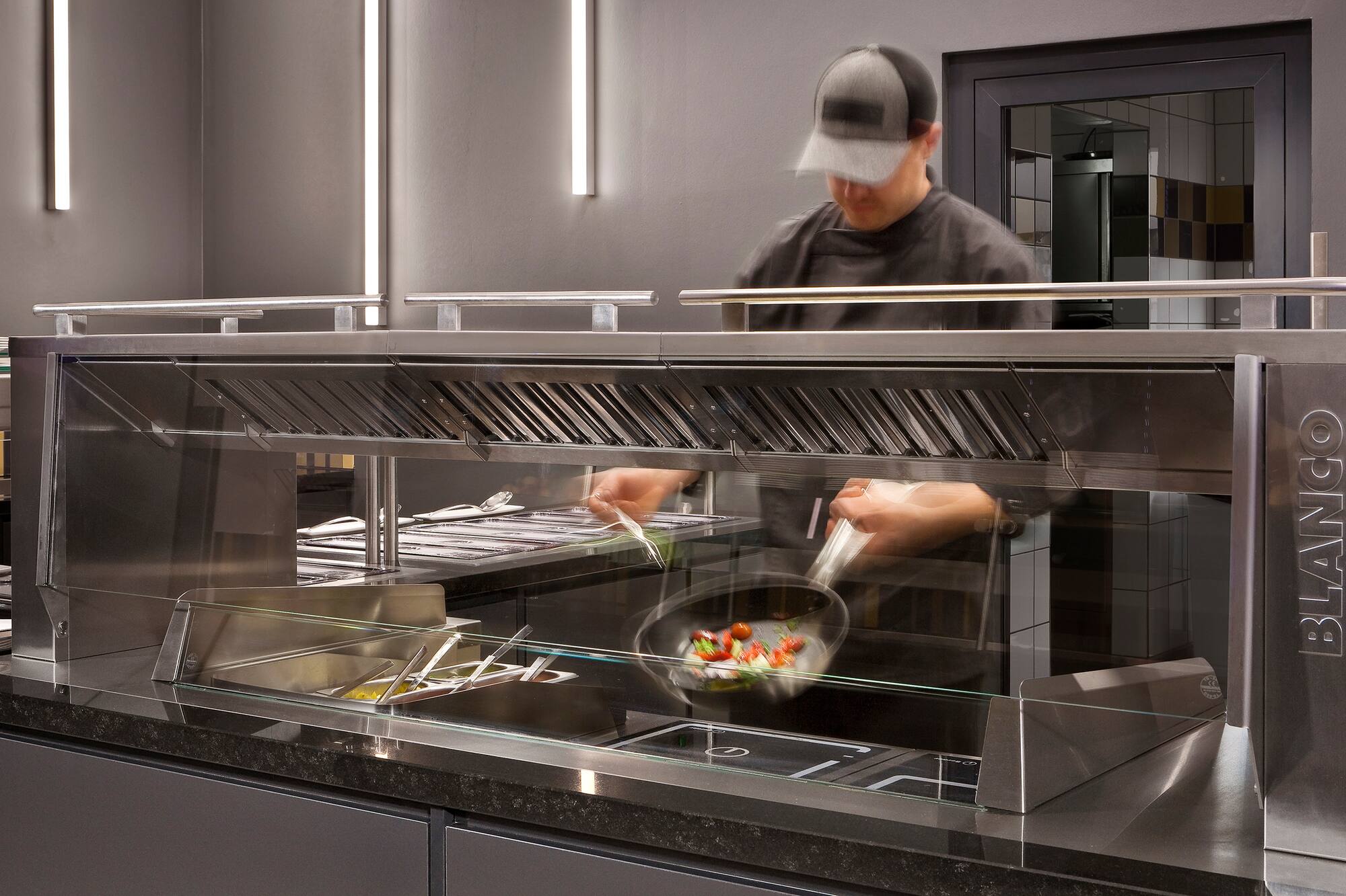 Chef cooking at BLANCO live cooking station with induction hobs.