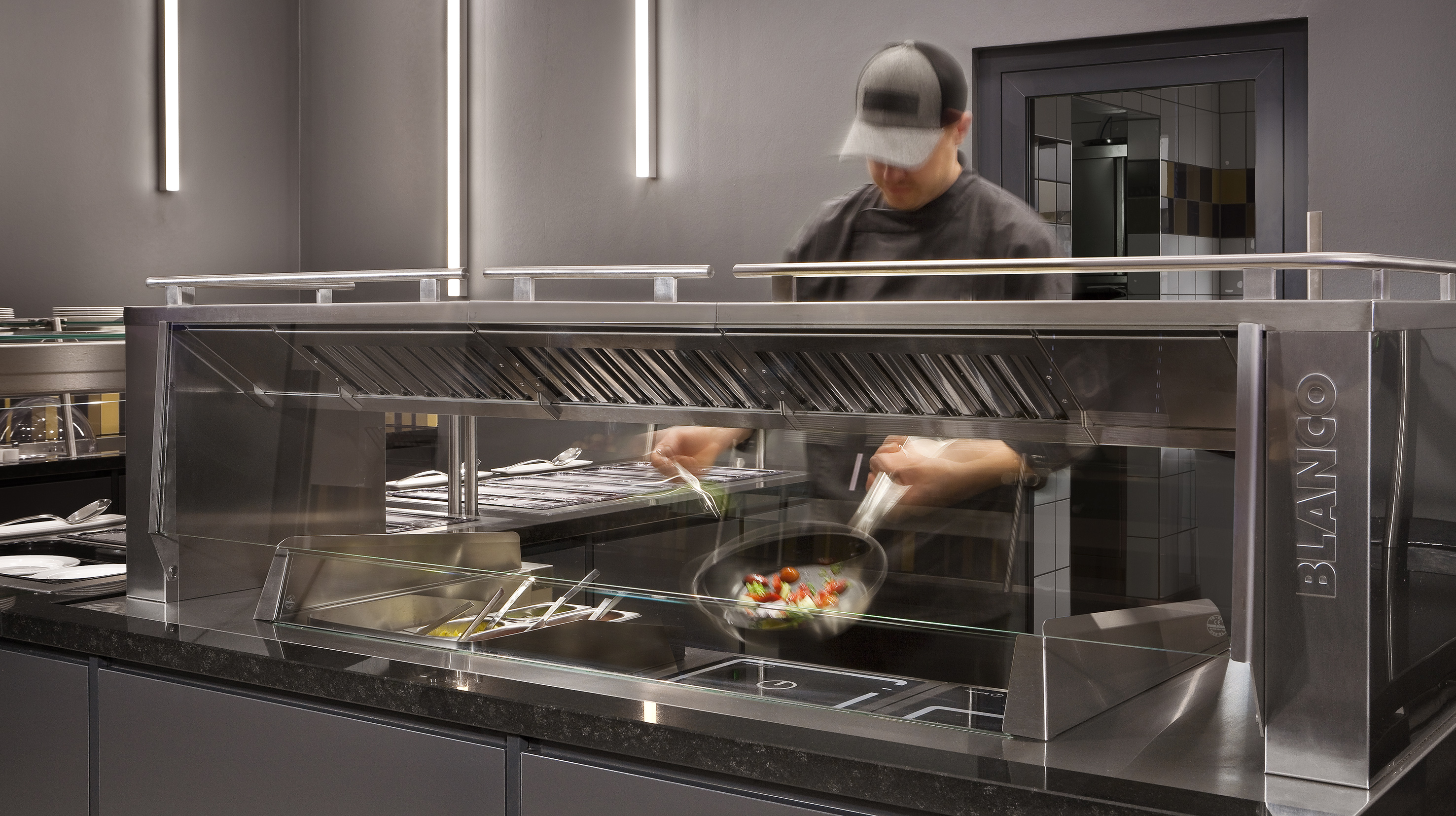 Chef cooking at BLANCO live cooking station with induction hobs.