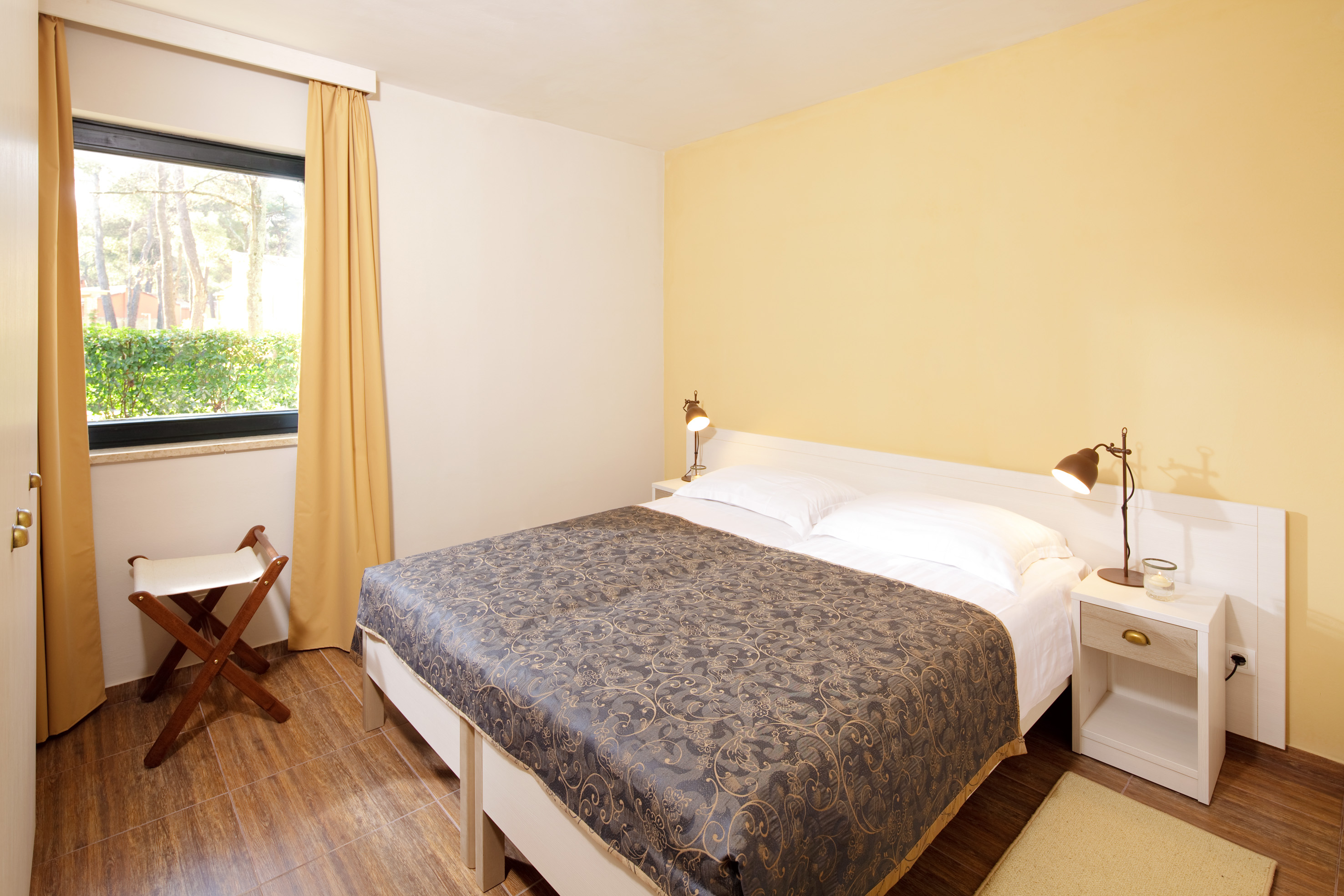 a bed with two lamps and a chair in a room