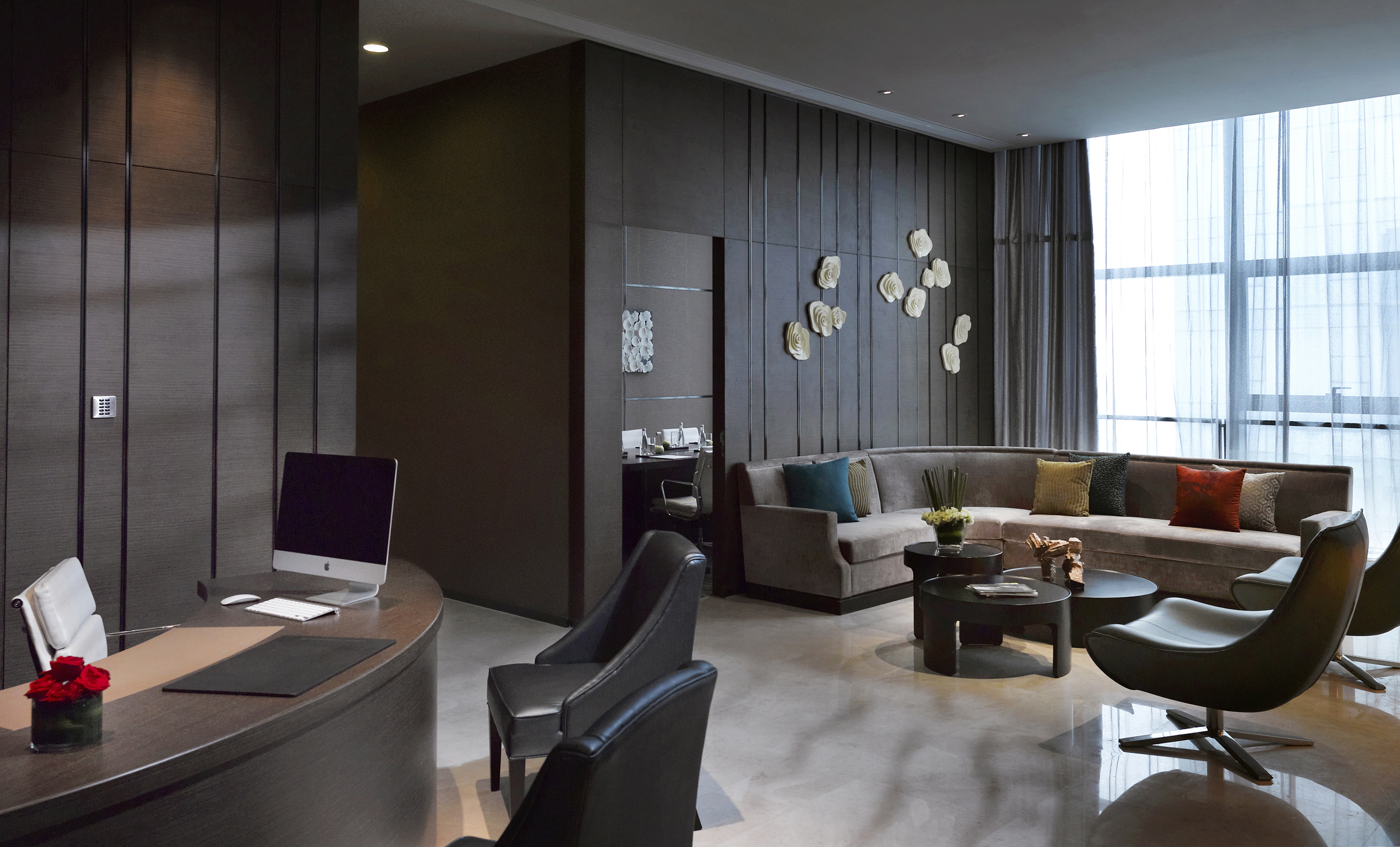 Hotel reception and lounge with dark wood design and curved sofa seating.
