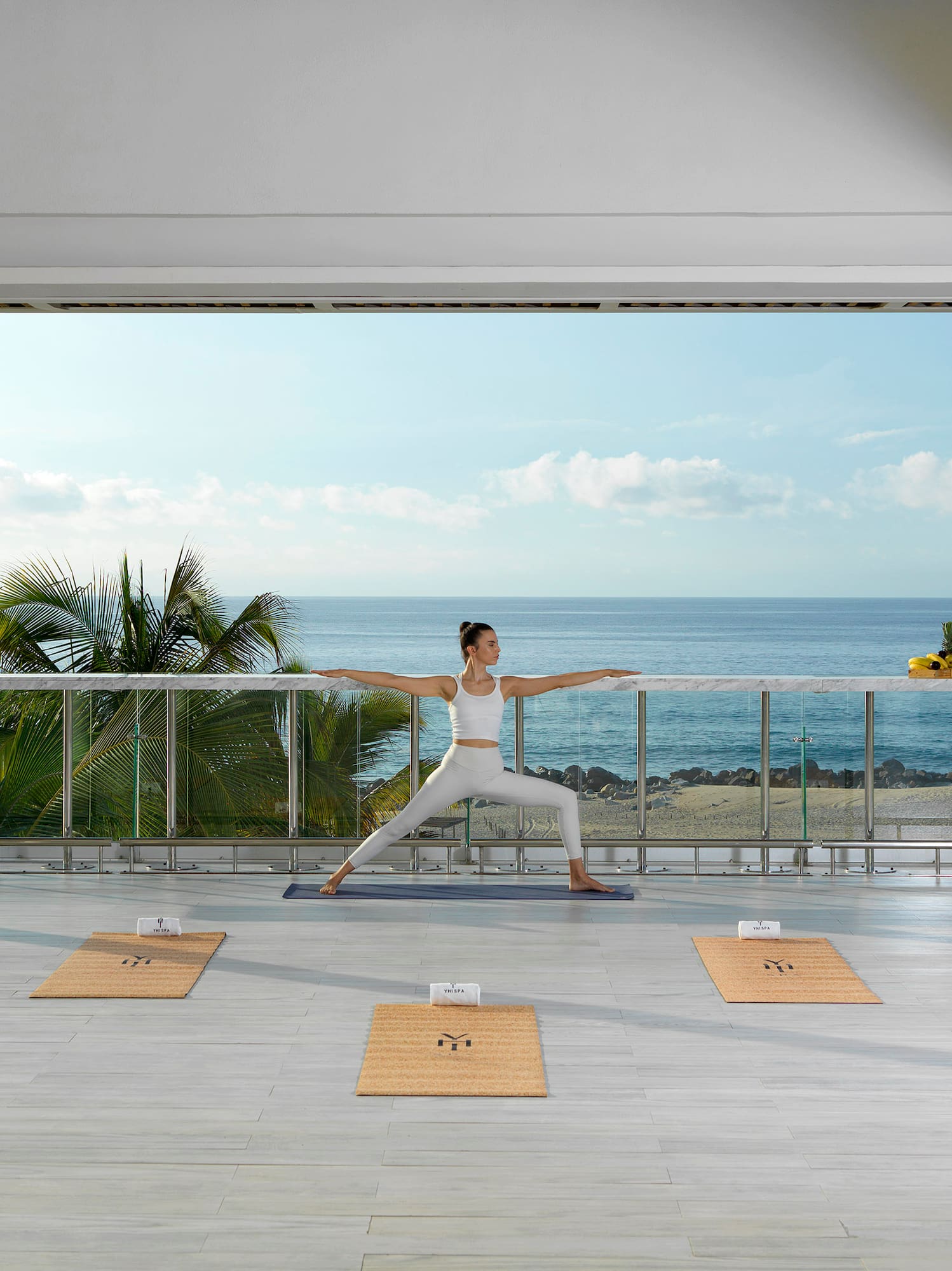 a woman doing yoga on a balcony overlooking the ocean
