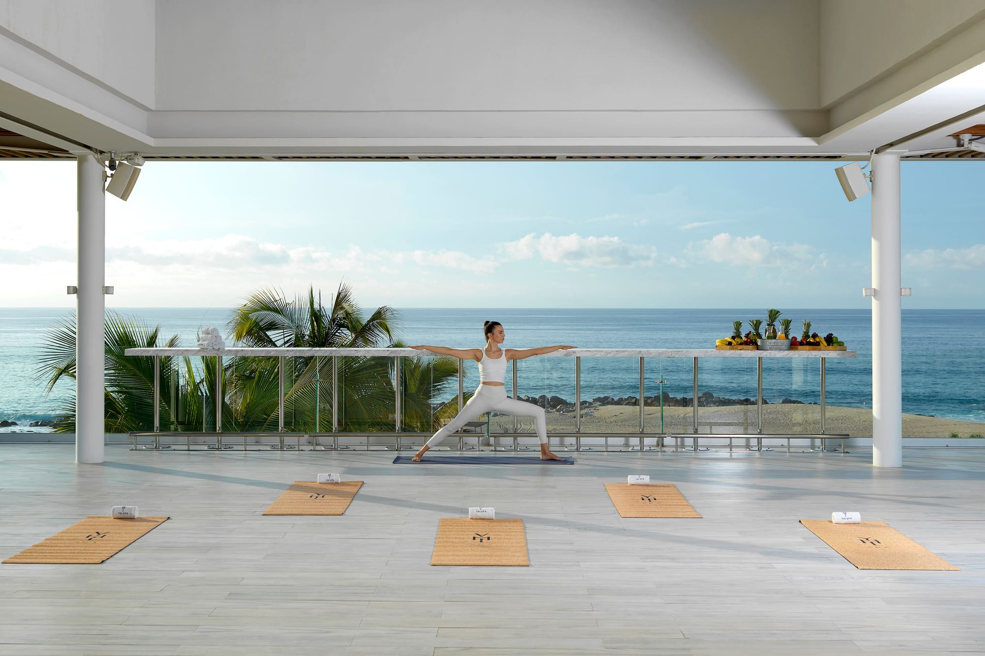 a woman doing yoga on a balcony overlooking the ocean