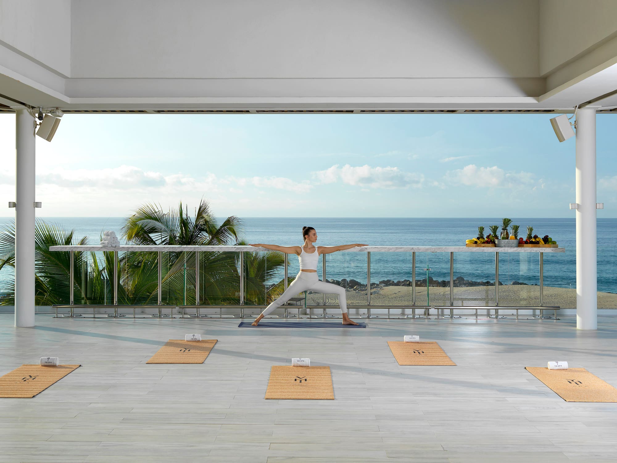 a woman doing yoga on a balcony overlooking the ocean