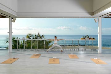 a woman doing yoga on a balcony overlooking the ocean