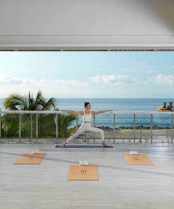 a woman doing yoga on a balcony overlooking the ocean