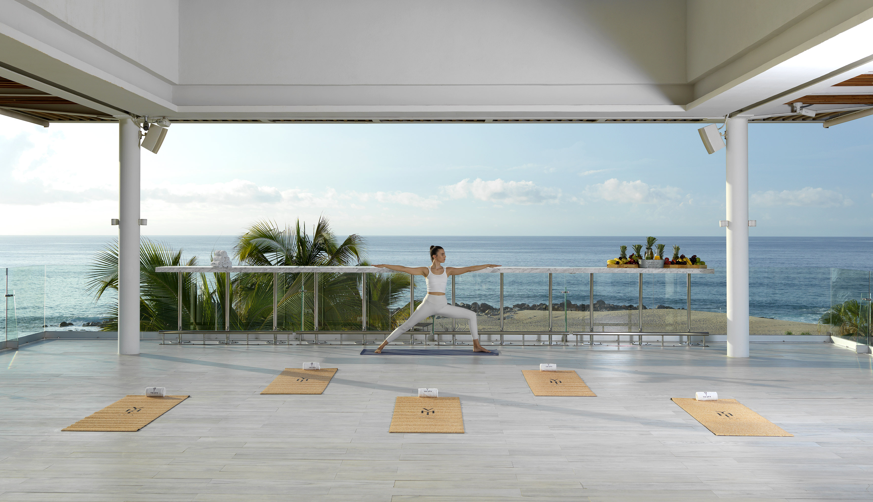 a woman doing yoga on a balcony overlooking the ocean