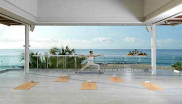 a woman doing yoga on a balcony overlooking the ocean